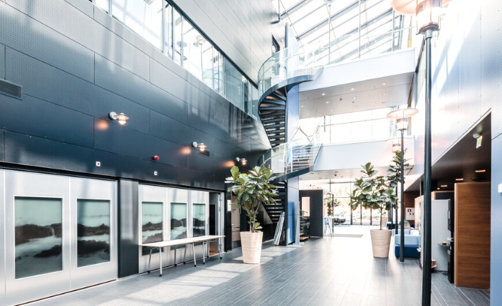 Sini-valko sävyinen ja aurinkoinen kuva toimistorakennuksen avarasta käytävästä Espoon Keilarannassa